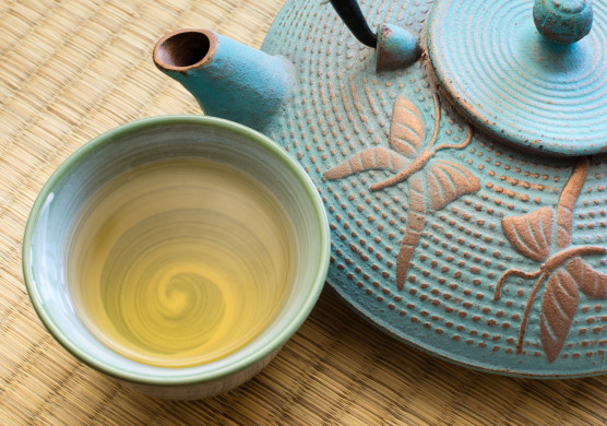 Oriental cast iron tea pot with tea cup on tatami mat