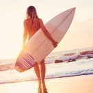 Surfer girl on the beach at sunset