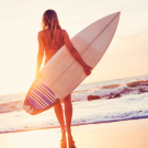 Surfer girl on the beach at sunset