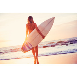 Surfer girl on the beach at sunset